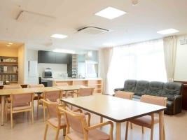 木製の椅子と机が置いてある部屋。奥にはカウンターキッチンも見える