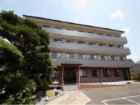 入口にスロープが設置され、手前に駐車場がある施設の外観