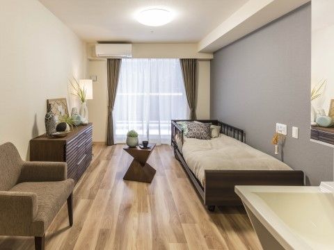 ブラウンで揃えられたベッド、タンス、ソファ、テーブルが置かれた部屋