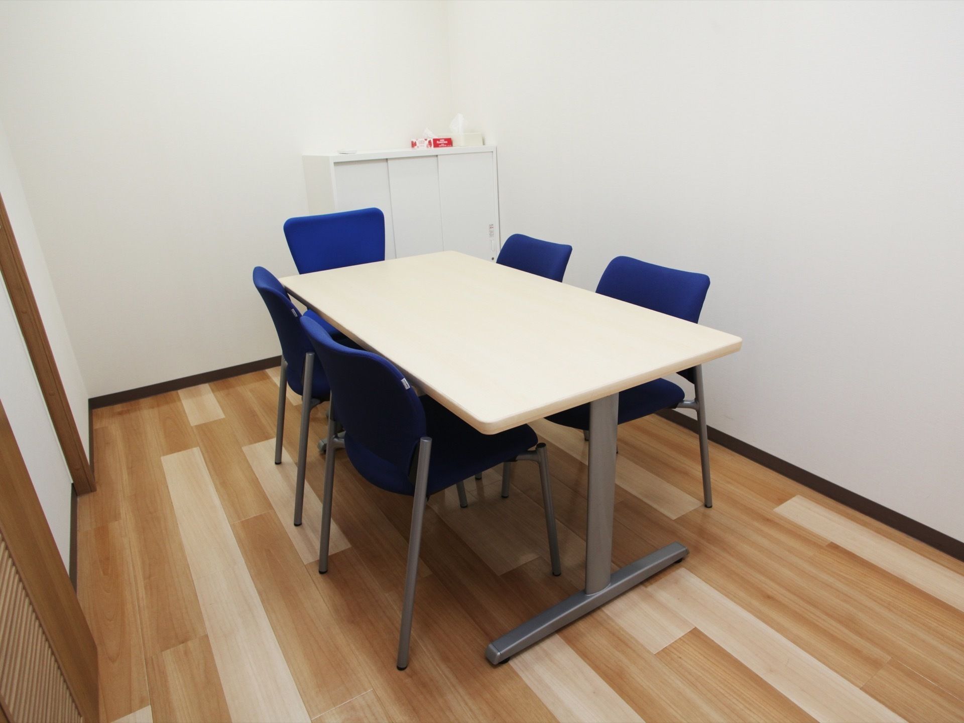 部屋の角には、三枚引き戸のキャビネットが設置されている。キャビネットの上には、ティッシュなどが置かれている。