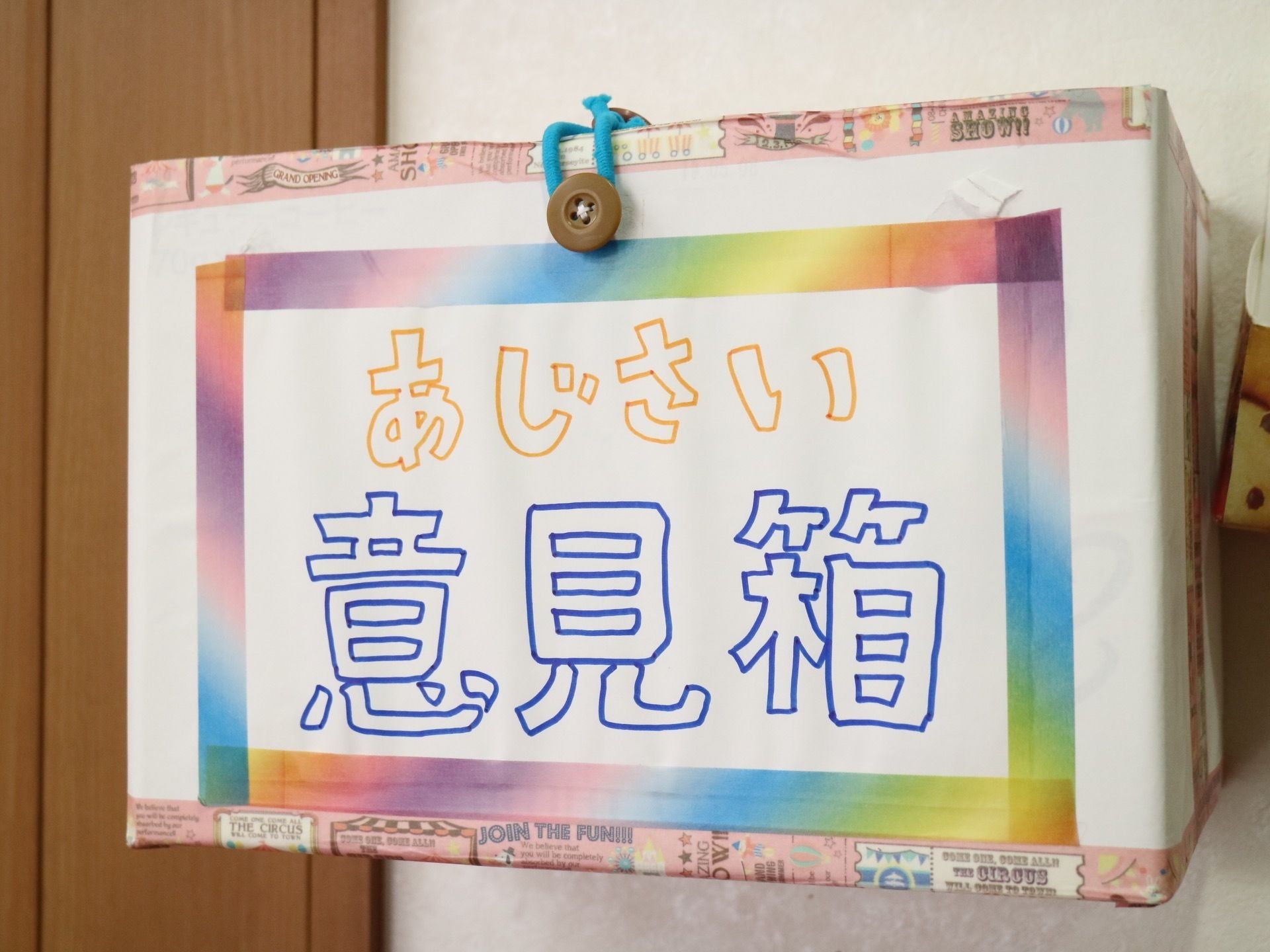 施設内の白色の壁に、意見箱がある。マスキングテープやボタンが装飾に使われた手作りの意見箱である。