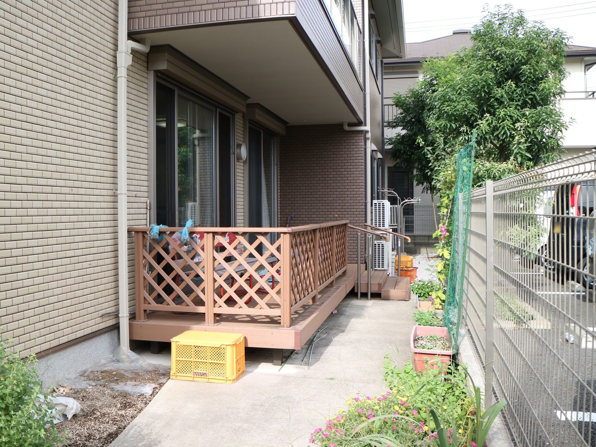 施設の建物の１階に設けられたウッドデッキからも出入りすることができる庭である。長方形のプランターも並べられている。