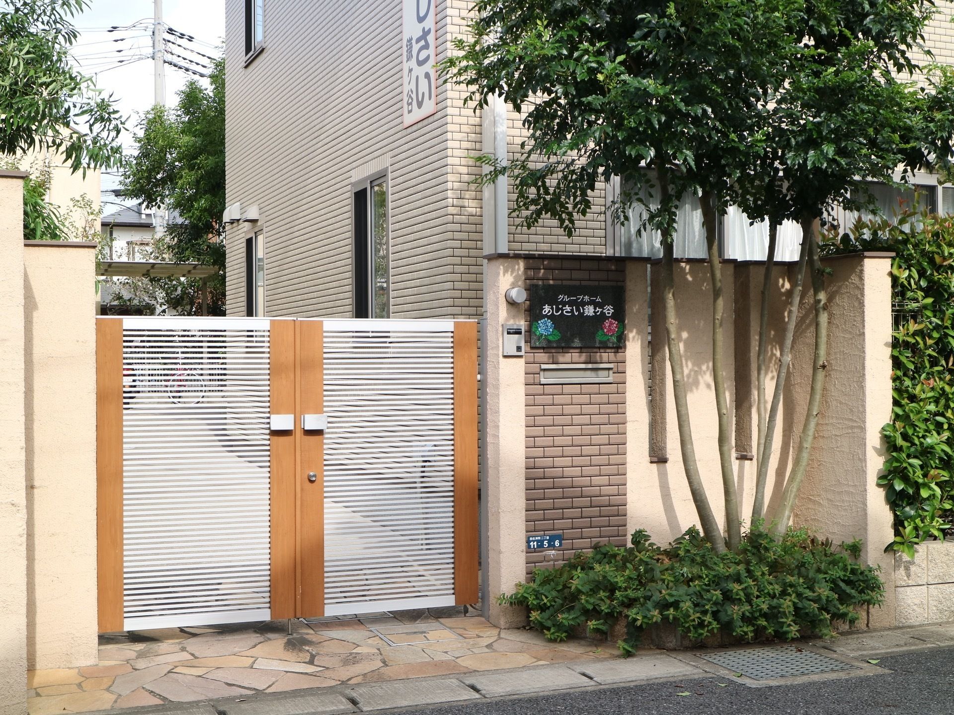 施設の外壁はレンガ張りで、敷地は全面塀に囲われている。門のそばには、インターフォンと黒色の表札がある。