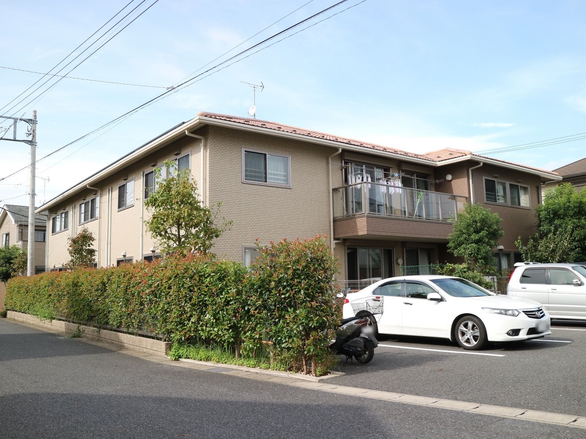 壁は細かいベージュのタイルを張り、屋根にオレンジ色のレンガを付けている。２階の窓には柵が横に付いている。