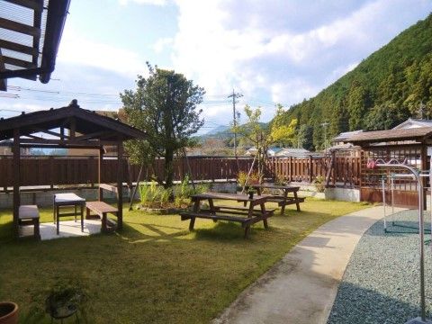 ベンチとテーブルが置かれ、木が植えられた、山を望める芝生の庭