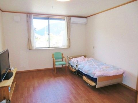テレビとベッド、椅子が備え付けられた一人暮らし向きの部屋