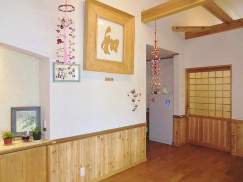 白と木目の茶色の壁、濃い茶色の床で暖かみが感じられる。手すりや大きなドアがついている。壁には木の額縁に入った文字が飾られている。