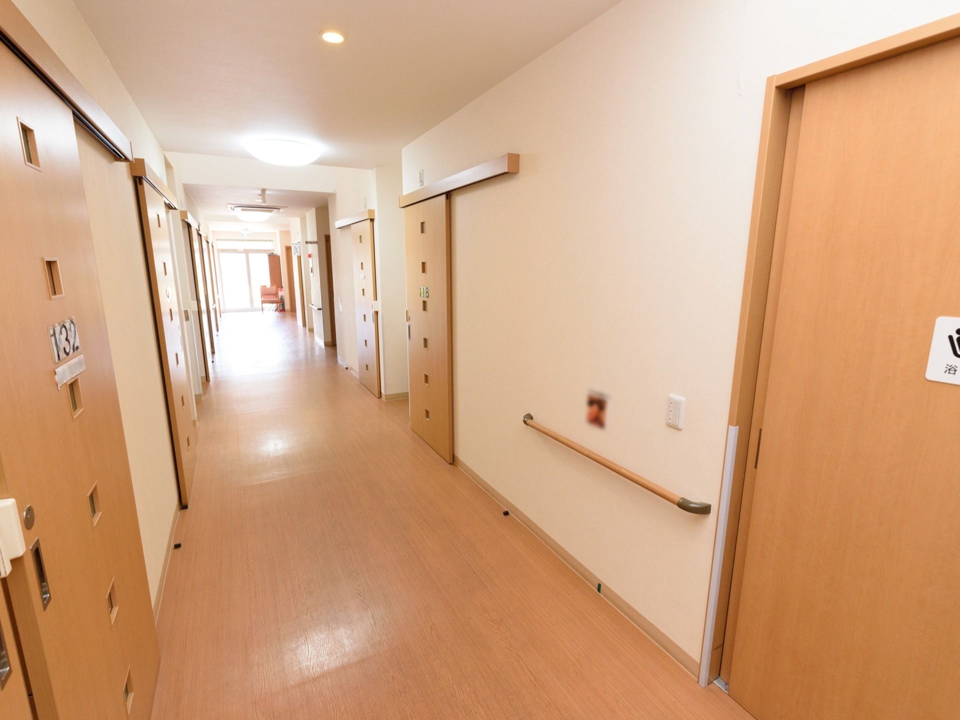 廊下の両脇に、たくさんの居室のドアが並んでいる。ドアには明かり取りの小さな窓が複数付いており、部屋番号が貼られている。
