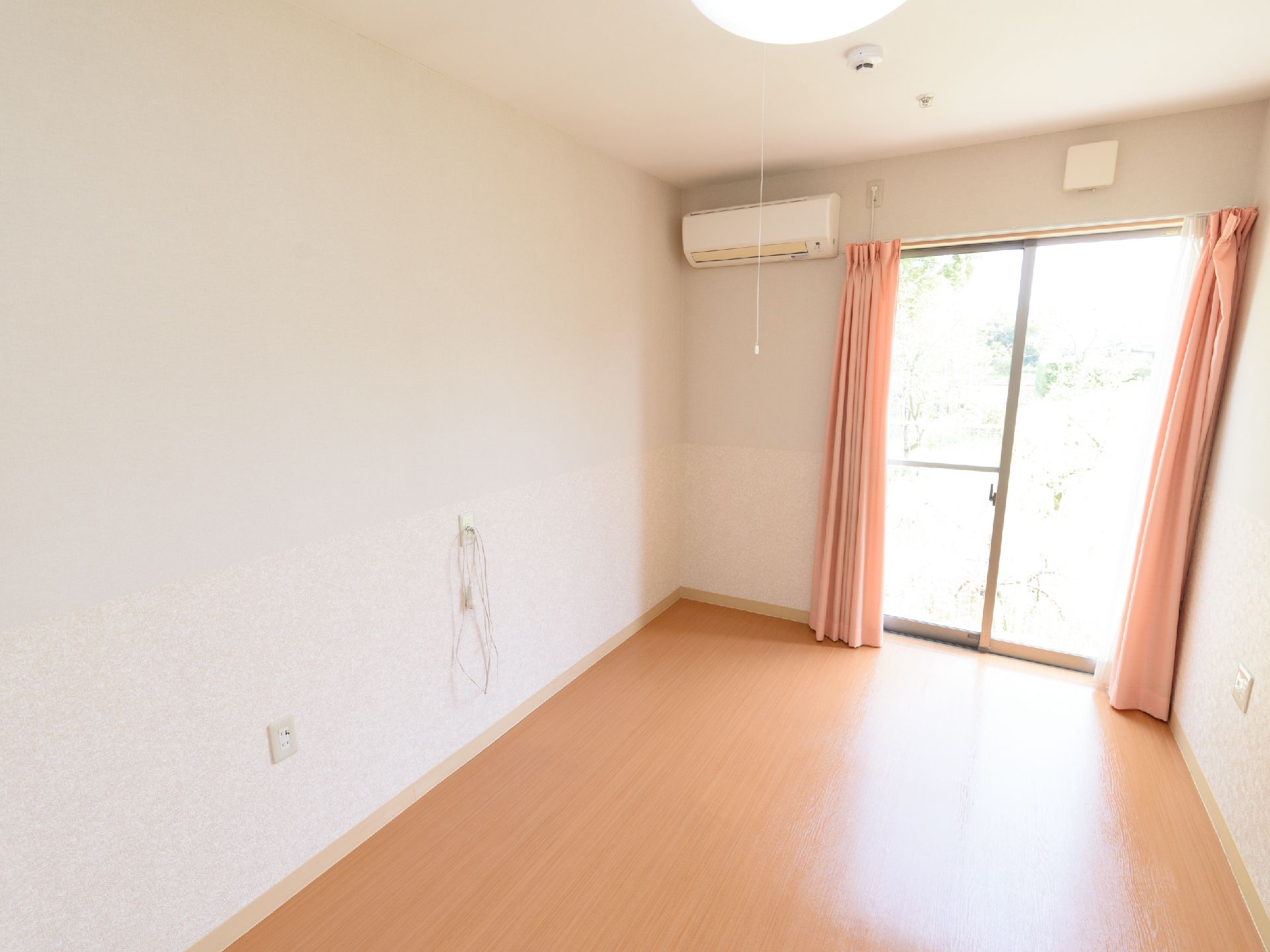 カーテンとエアコンがつけられた、一人暮らし用のワンルーム