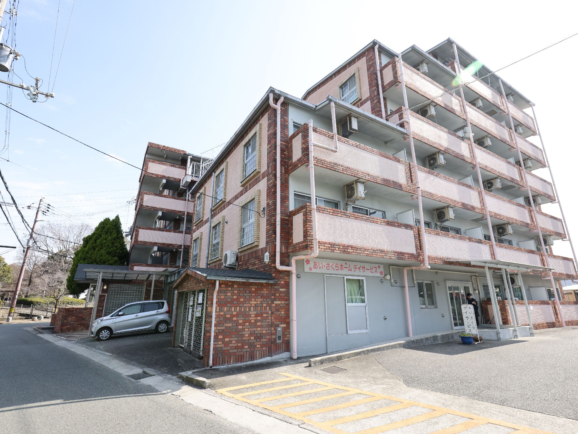 広い駐車場が隣接している、おしゃれな屋根のある介護施設