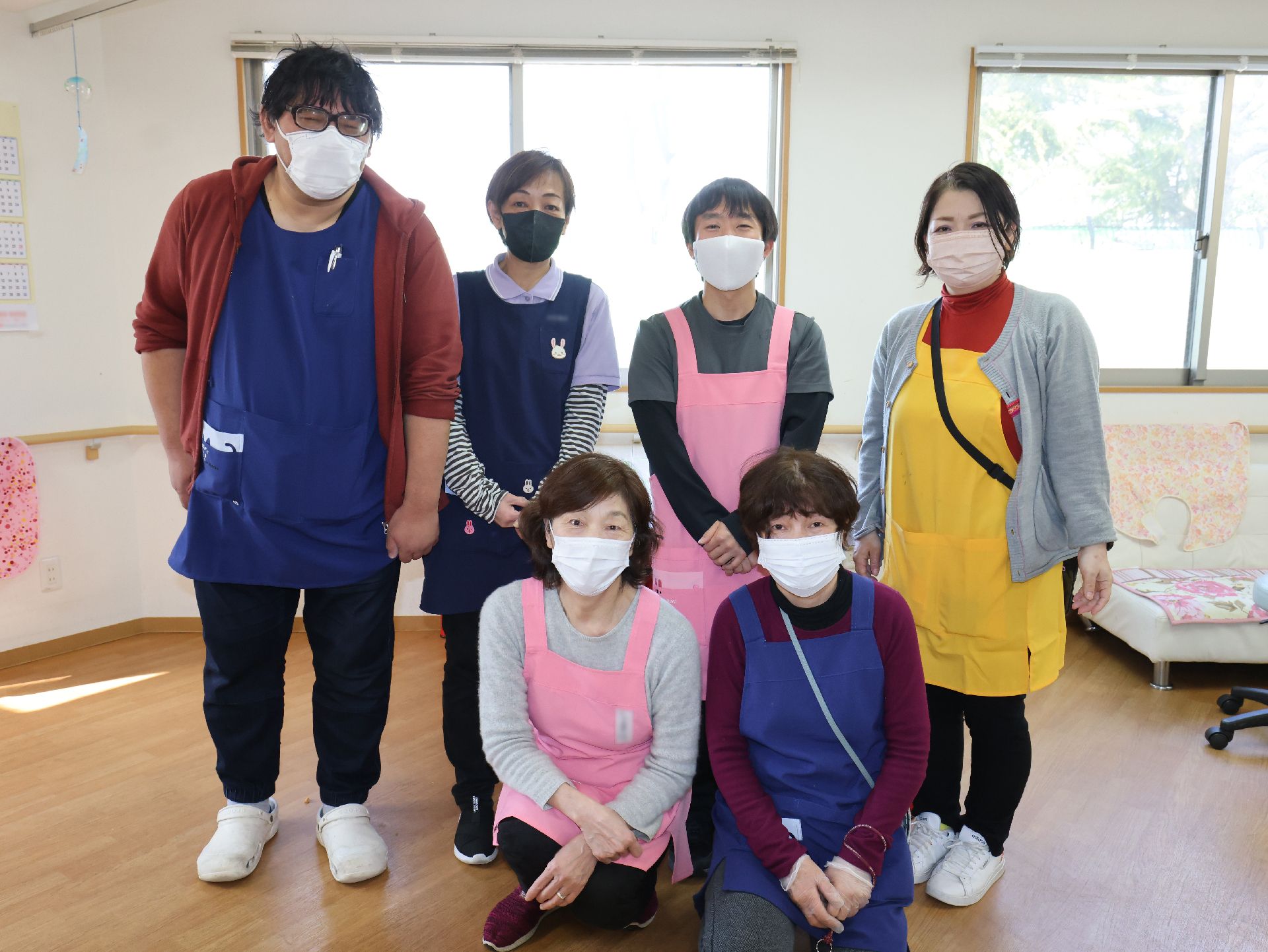赤いトレーニング器具を引っ張りリハビリをする高齢女性と理学療法士の男性