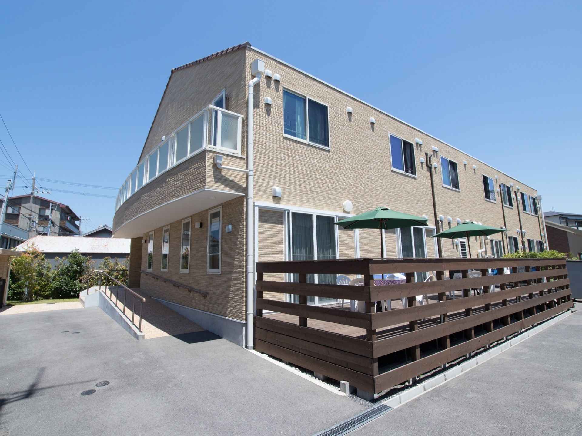 ２階建ての建物の１階部分にはウッドデッキがある。パラソルやテーブルセットが用意され開放的なスペースになっている。