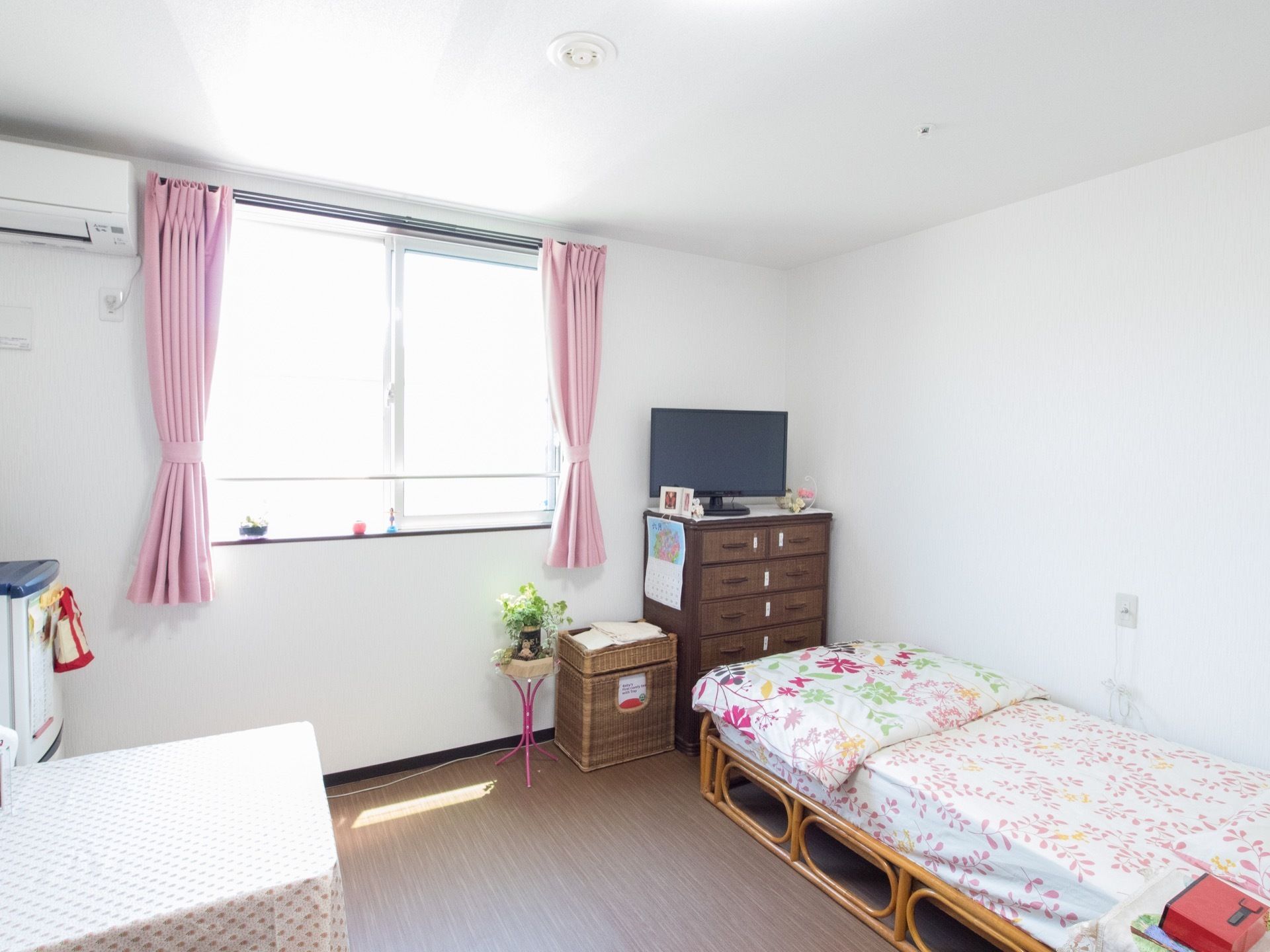 引き出しや小型の収納、テレビなどの家具を一式整えた居室の様子である。窓の桟の部分には、愛らしい小物が複数配置されている。