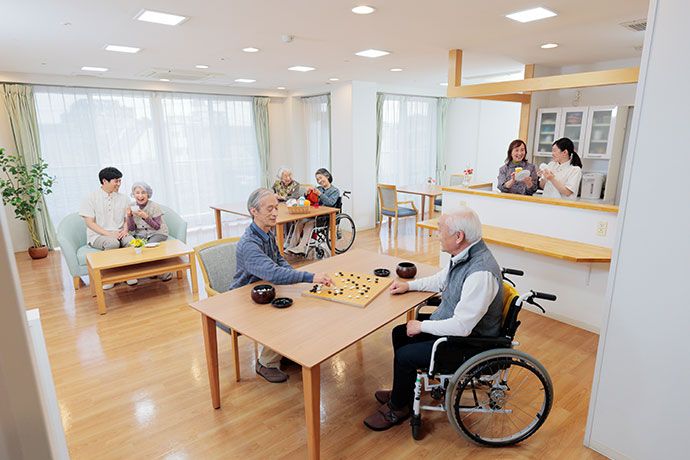 両手にピンク色の布を持ってスタッフと一緒に体操する入居者様