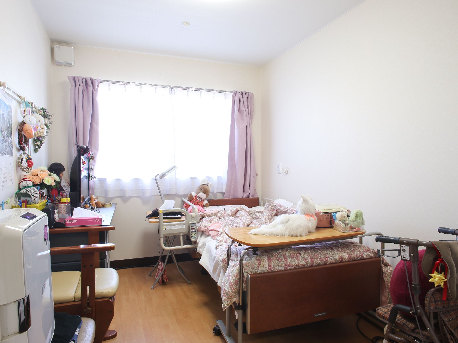 カスタマイズされた入居者用の部屋。カーテンは紫色を採用、ぬいぐるみや人形などの置物、また花が飾ってある。