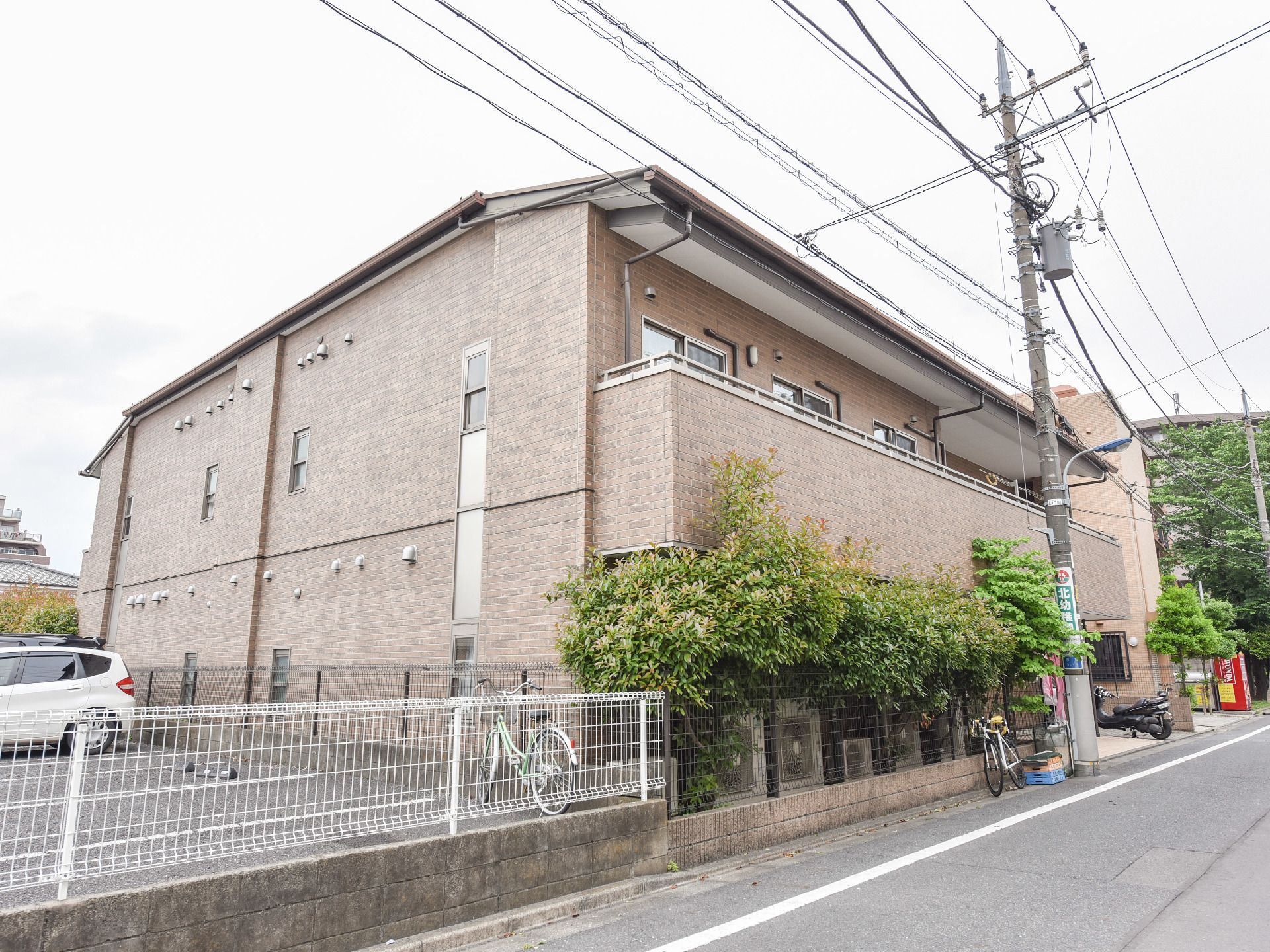 落ち着いたレンガ調の建物に、植木が緑を添えている。ベランダの壁は少し高めに作られており、転落防止にも配慮されている。