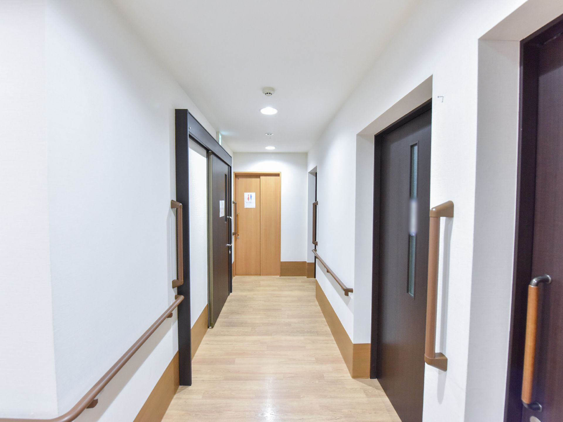廊下の床には段差がなく、トイレ付近までフラットなフロアが続いている。左右の壁には歩行をサポートする手すりがある。