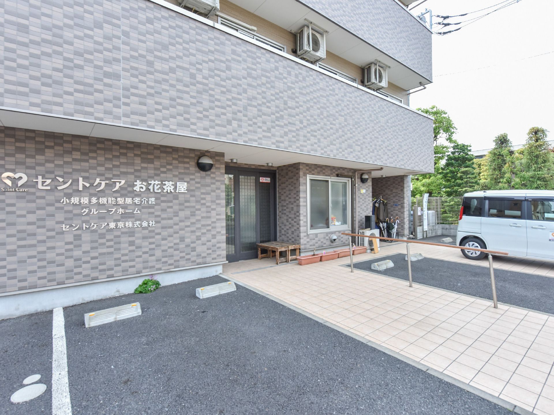 ベンチが置かれた扉横の壁に大きく施設名が表示されている玄関前
