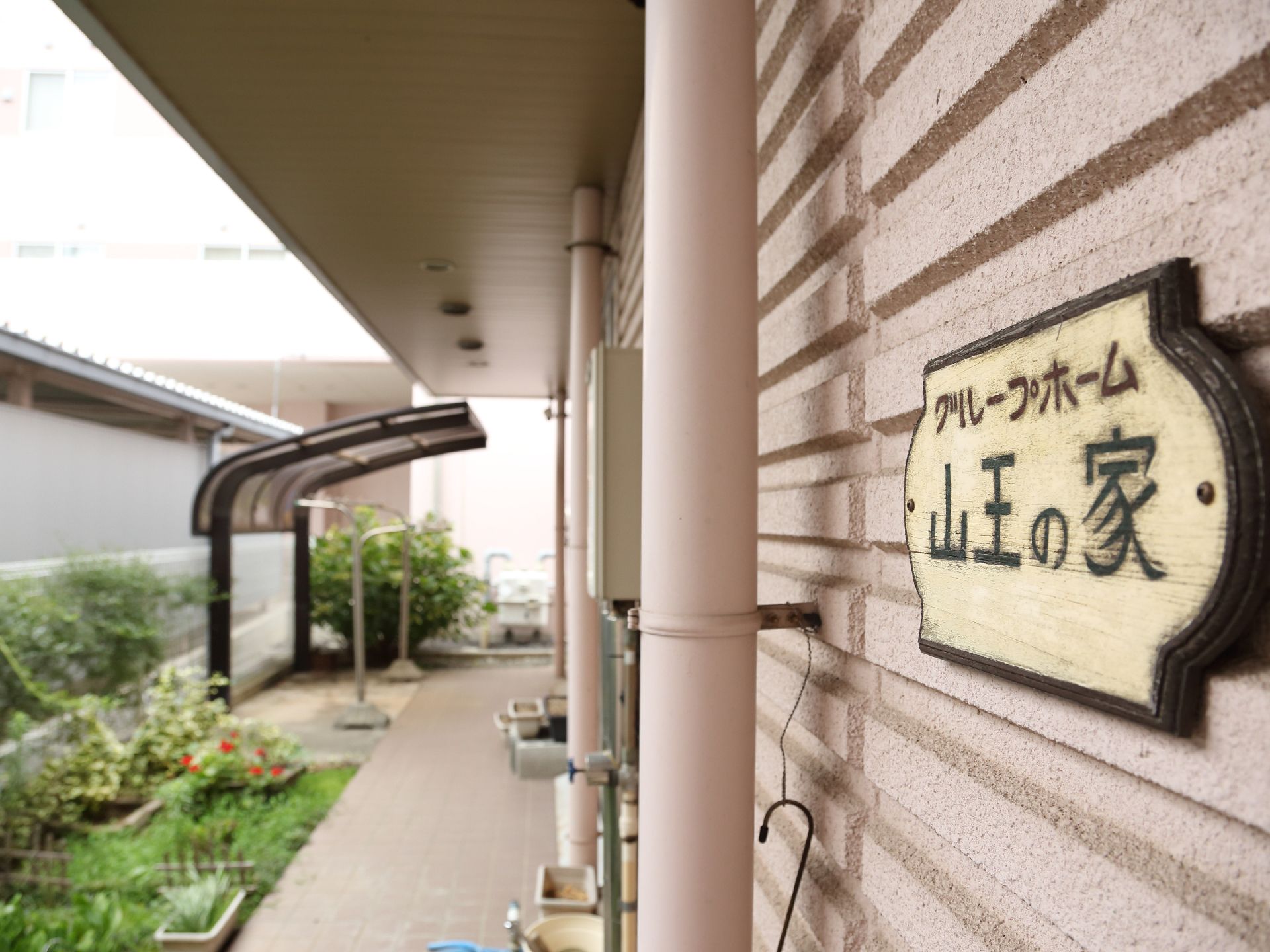 木材で作られた看板が壁に取り付けられているピンク色の外壁