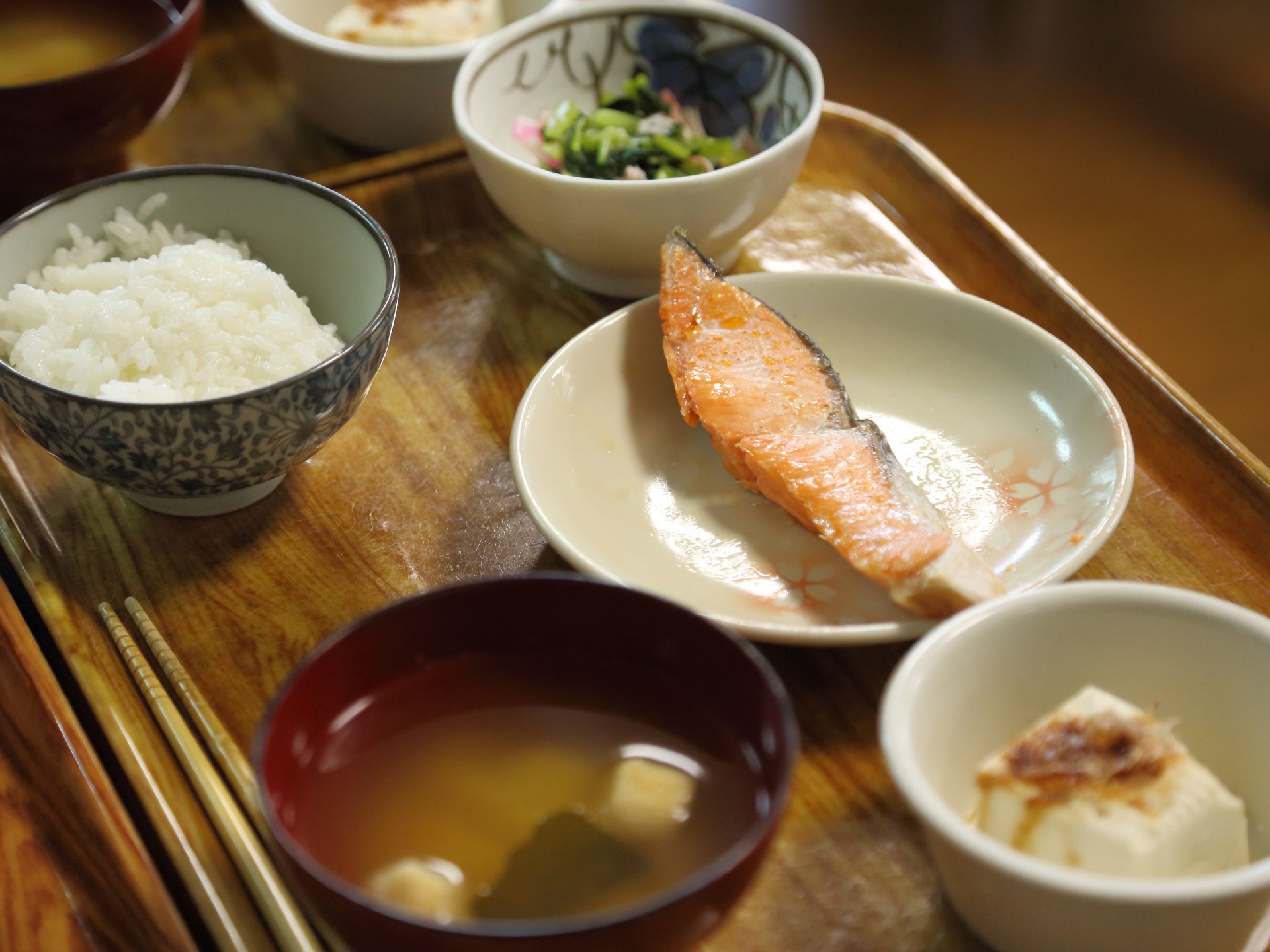 トレーに乗せられた食事。メインは鮭の切り身で、副菜に小鉢と冷奴が添えられている。ごはんの盛りは健康に留意した八分目。