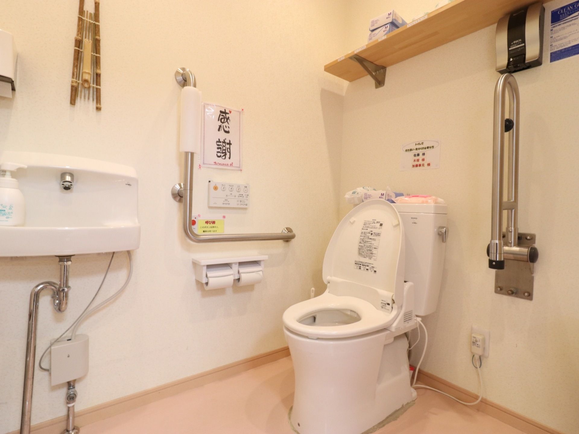 トイレにはフタの空いた便座が設置されており、両サイドには手すりがついている。壁には「感謝」と書かれた貼り紙がある。
