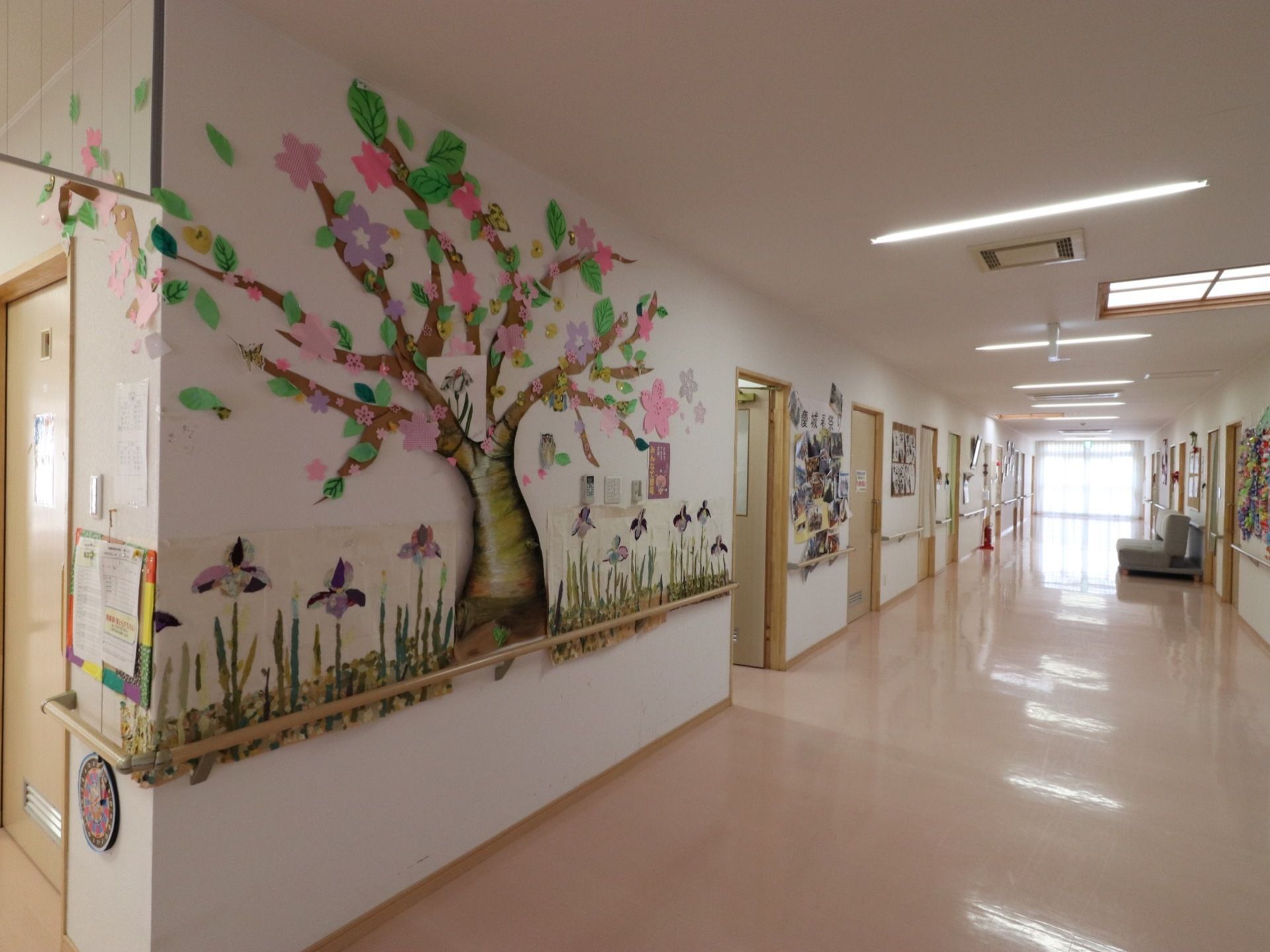 通路は広いスペースとなっており、奥にはソファがある。壁際にはドアのほか、桜の木を模した工作が貼られている。
