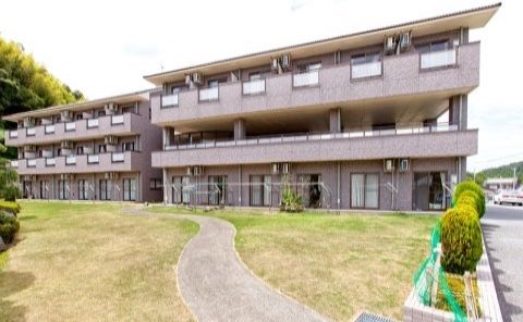 ブラウンの外壁で落ち着いた雰囲気の大きな建物である。木々が植えられており、自然に触れることができる環境である。
