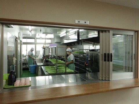 明るく清潔な空間に、ステンレス製の台が設置されている。厨房で作業するスタッフは皆エプロン・マスク・帽子を着用し、衛生面も考慮されている。