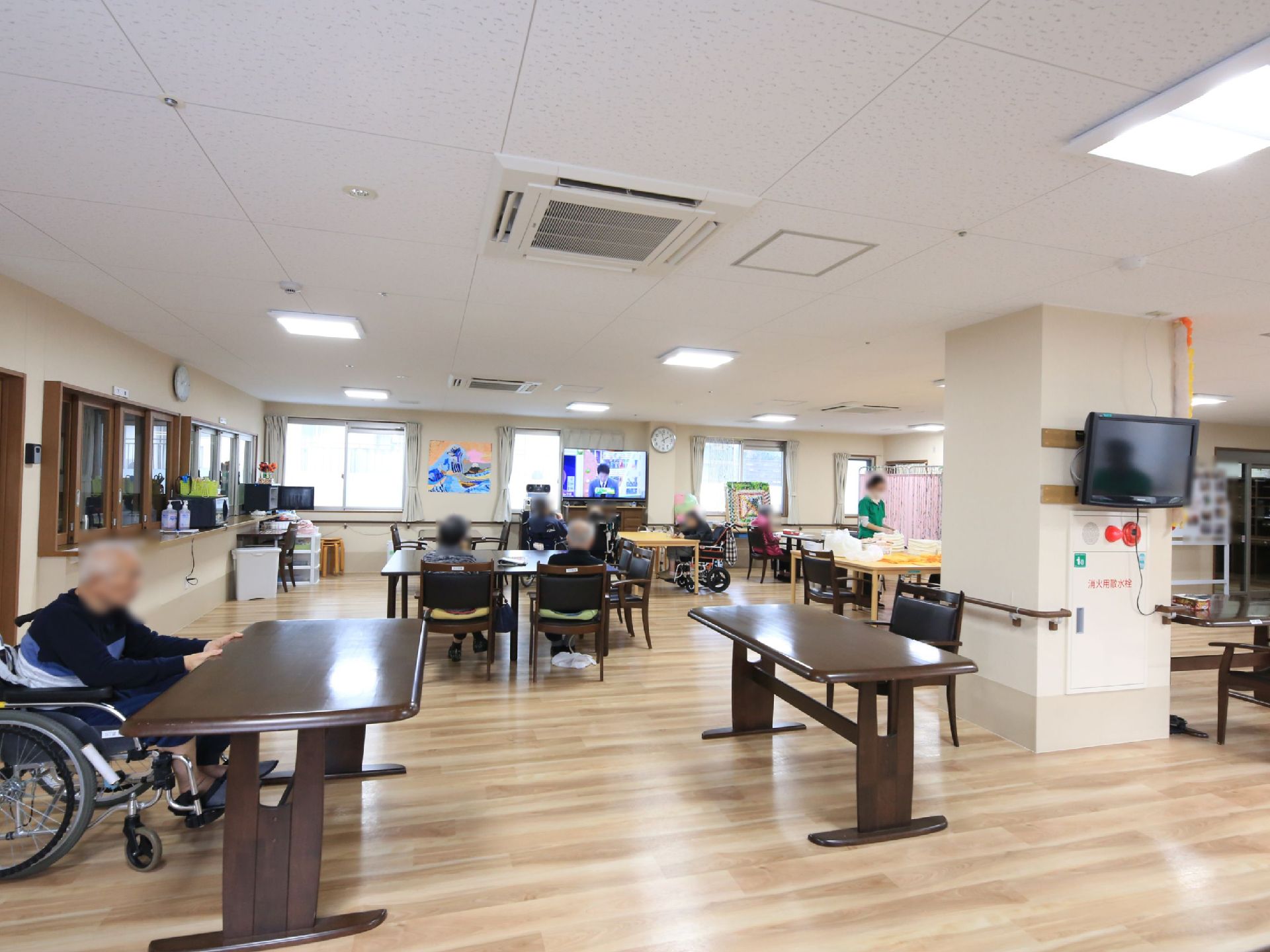食堂兼機能訓練室は広々とした空間である。厨房が併設されており、ダイニングテーブルが並べられている。正面の窓際に大型テレビが設置されている。