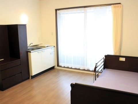 カーテンが開いた窓の横に小型キッチンが備え付けられた部屋