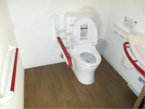トイレは白色の壁で清潔感のある作りとなっている。手すりが赤くなっているので、見つけやすく安全に利用できる。