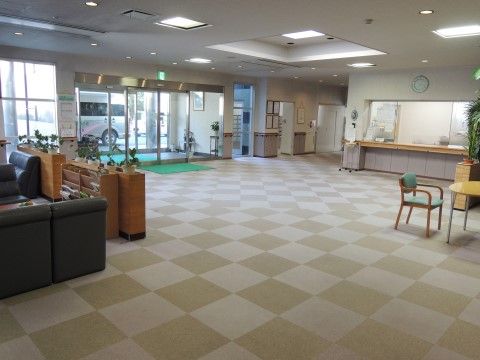 広いエントランスには、ベージュのカーペットが敷かれている。間口が広いカウンターがあり、奥は事務所になっている。