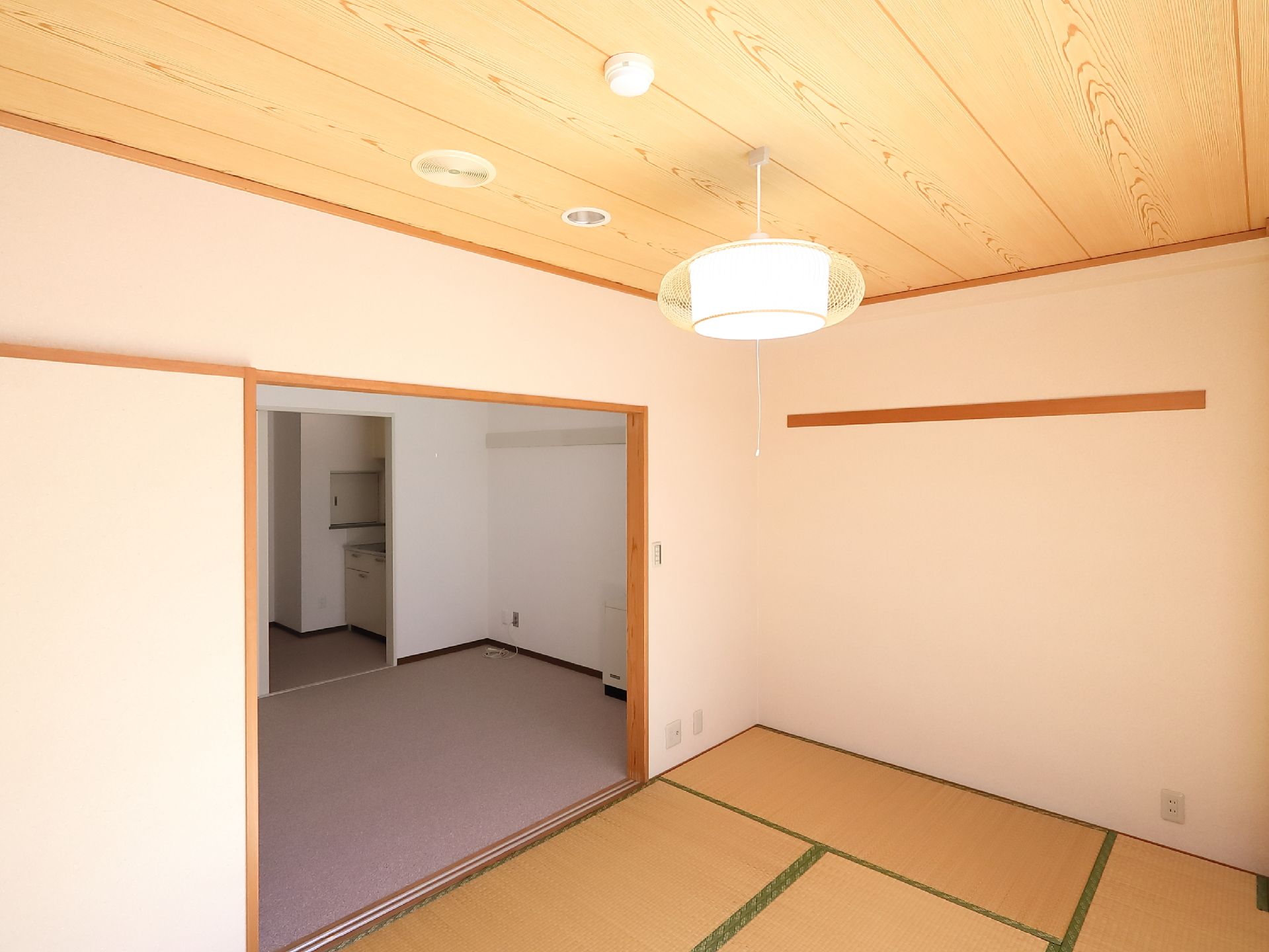 居室にある和室は窓に面している。奥に洋間があり、キッチンが併設されている。壁にコンセントが取りつけられている。