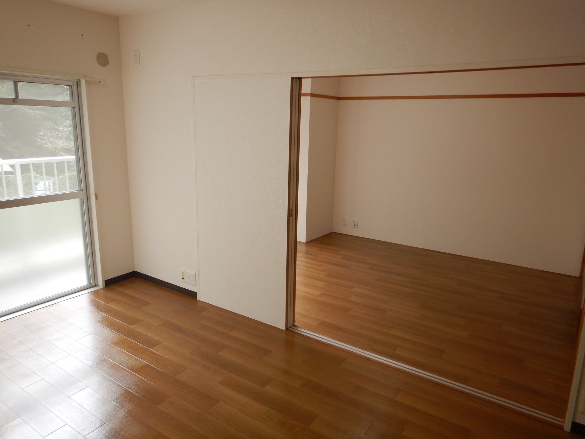 洋間が２部屋あるタイプの居室である。手前の部屋にはベッドが２台並べられている。奥の部屋にソファセットが置かれている。