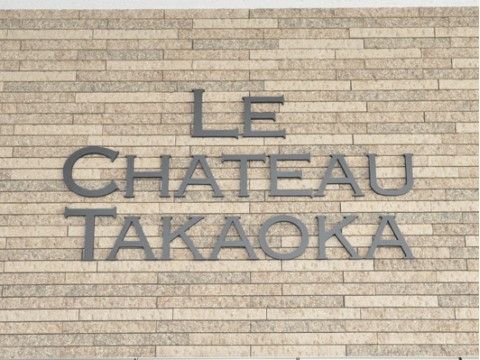 茶色の細長い石を使った外壁に取り付けられている施設名の看板