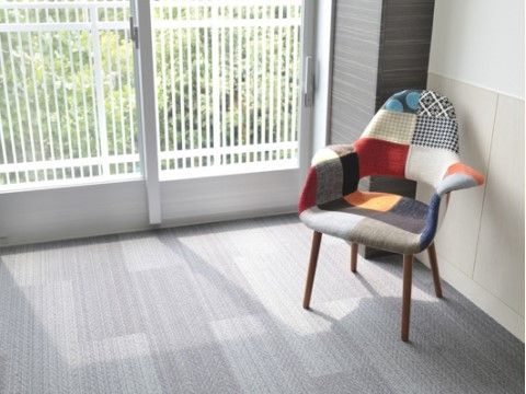 窓の前にパッチワーク柄の１人用ソファが置かれている居室