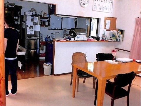 清潔感のある白い壁である。キッチンの背面には窓が付いていて通気が良さそうである。部屋の隅には消火器が配置されている。