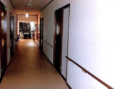 廊下の両側が入居者様の居室になっている。居室の入り口は木製の引き戸になっている。廊下の端に共有の洗面台がある。