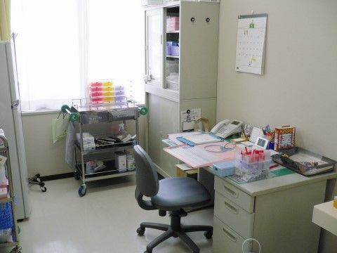 デジタル時計や固定電話が置かれたデスクがある事務所