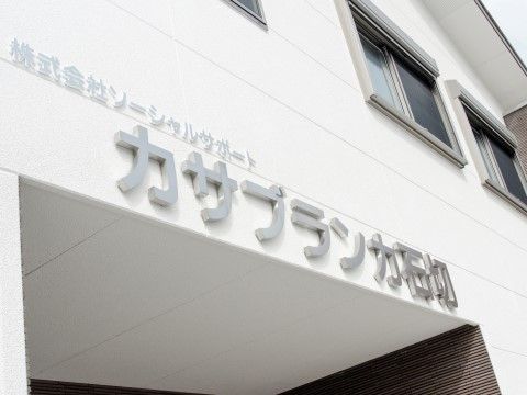 ステンレス板を抜いて作られた施設名称が壁に取り付けられた玄関