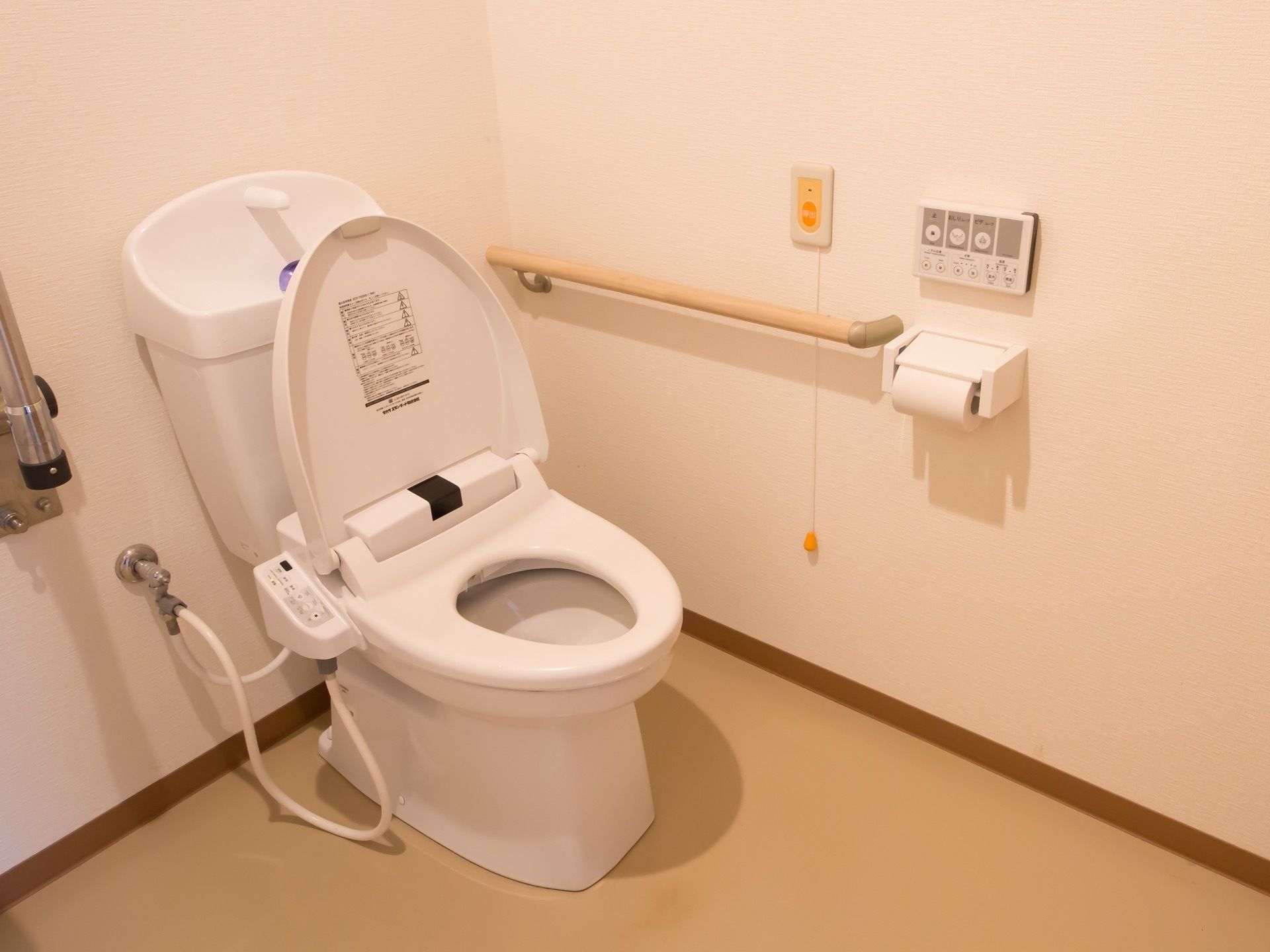 洋式の自動洗浄機能付きトイレである。便器の横の壁に、手すりやナースコール、洗浄器のリモコンが設置されている。