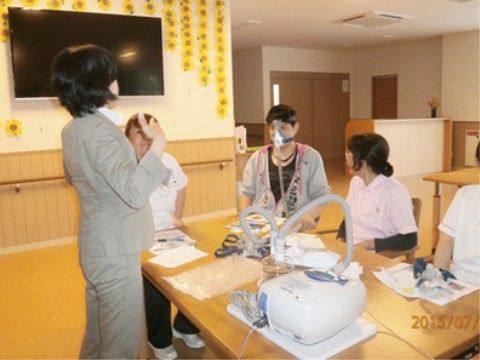 テーブルの周囲に集まって、講師の話を聞いているスタッフ