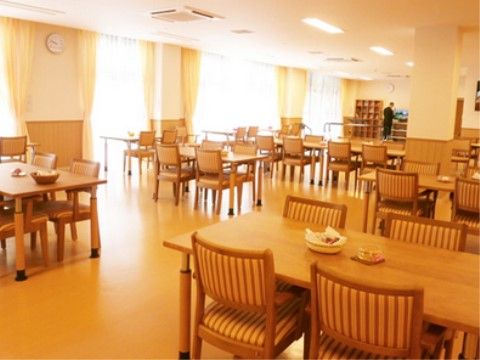 一面が窓になっており、日当たりも良好で明るい。通路も広く通行しやすい。４人掛けのダイニングセットが複数設置されている。