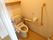 居室にあるトイレは入り口がアコーディオンカーテンにより仕切られている。便座には手すりと背もたれパットが設置されている。