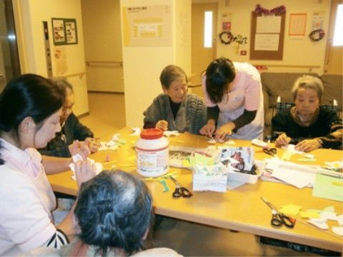 テーブルの周囲に集まって、スタッフと一緒に工作を楽しむ入居者様