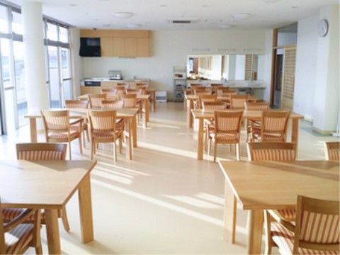 窓から日射しが差し込む明るい食堂である。４人掛けのダイニングテーブルとシステムキッチン、洗面スペース完備されている。