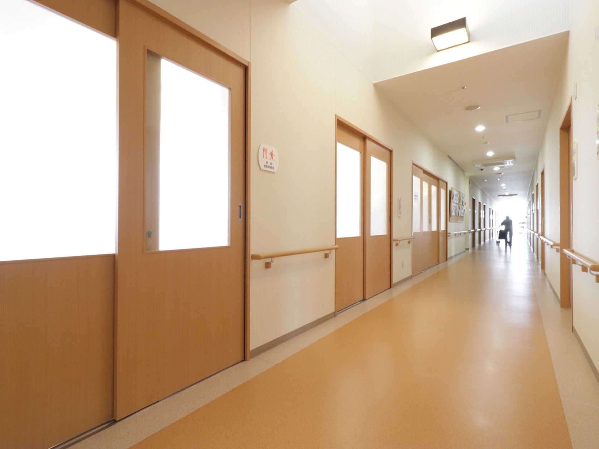 廊下沿いにある各部屋には番号や名前が振られているので、目的の部屋を見付けやすくなっている。両側の壁に手すりが備わっている。