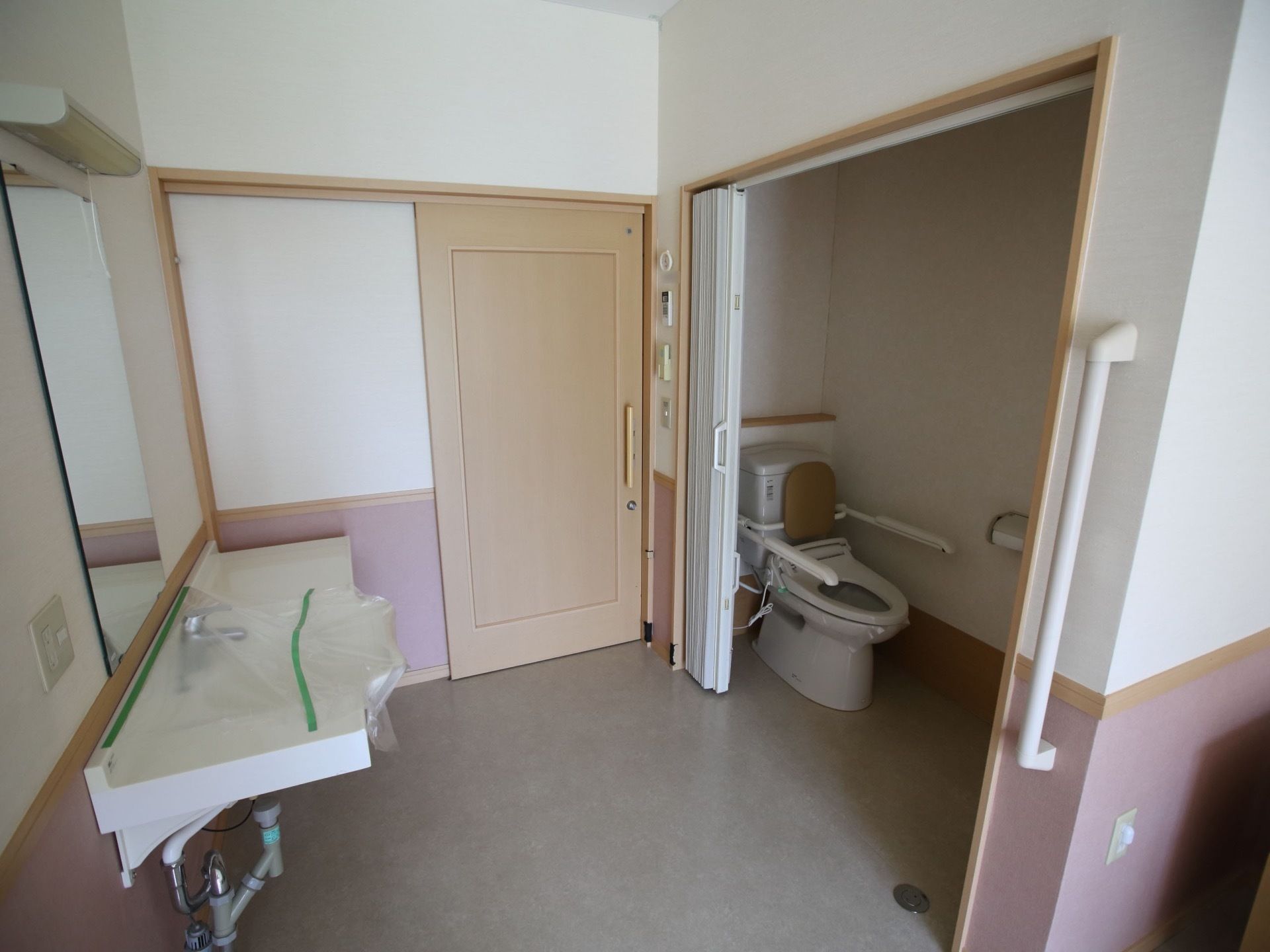 スライド式のドアが使用された居室で、入ってすぐ右側に洗面台があり、前の壁には大きな鏡が設置されている。