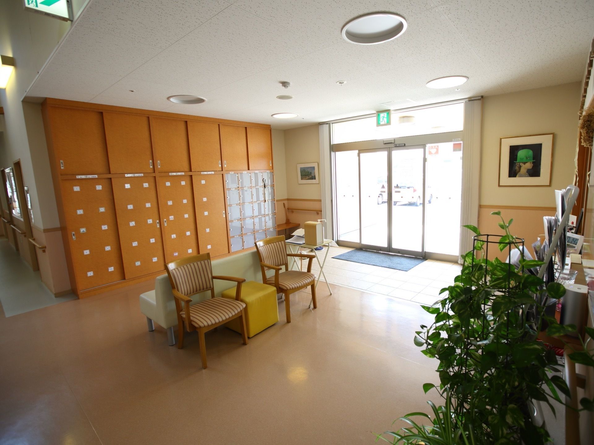 天井まで高さのある大きな下駄箱が設置されている。右側にはベンチがあり、近くの壁には手すりが取り付けられている。