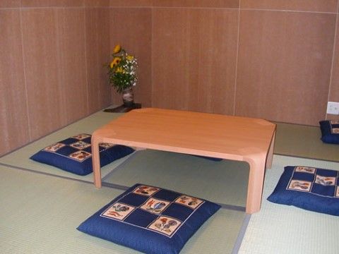 和室では、畳敷きに座卓が設置され、紺に柄の入った座布団が各位置に置かれ、和室の角には生け花が置かれている。